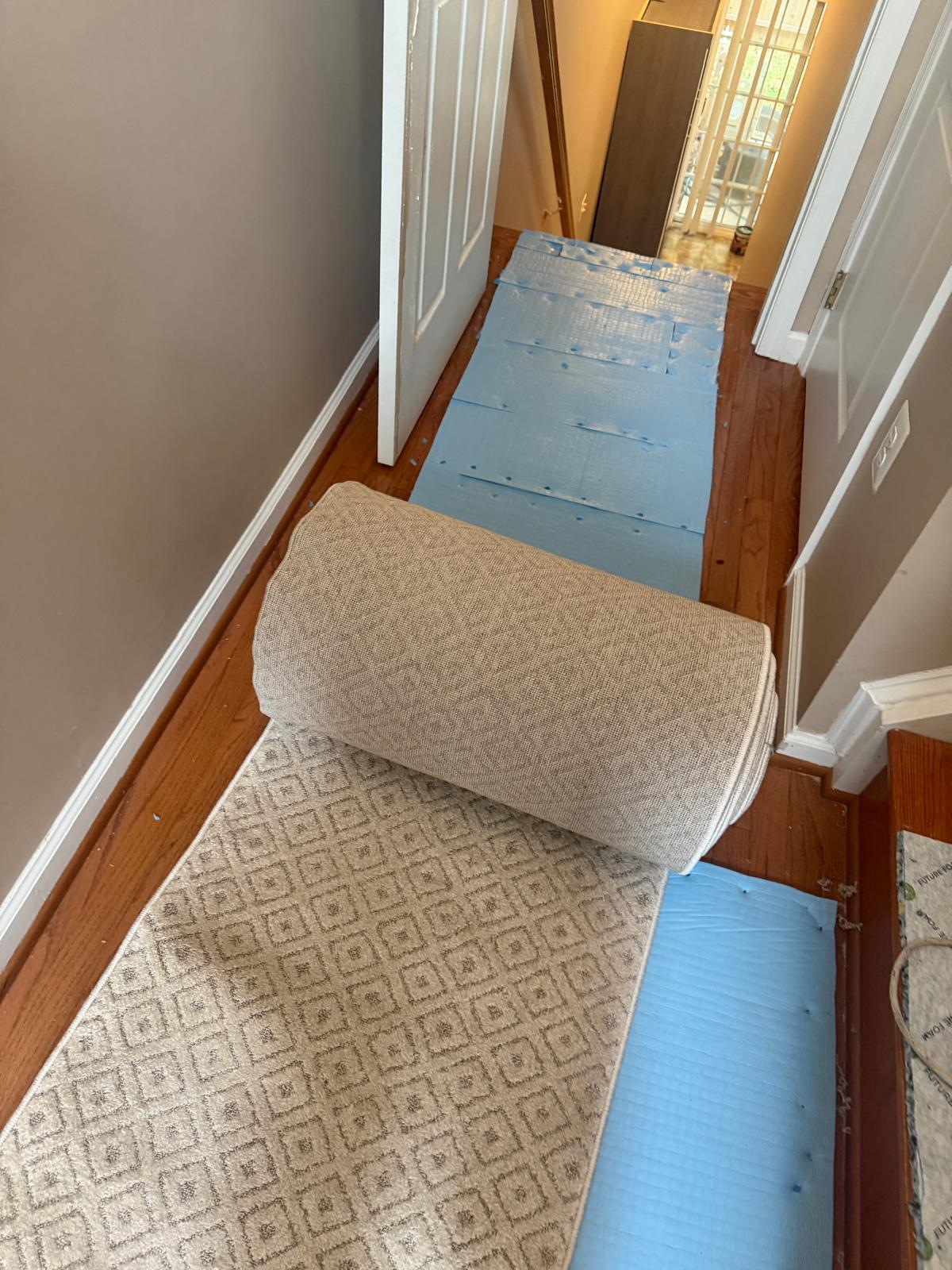 Hallway carpet runner being rolled out over new padding